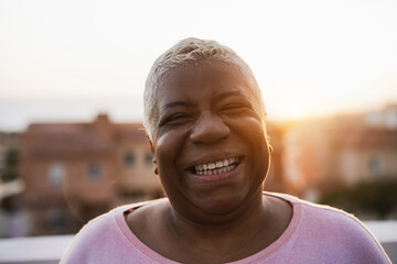 Wall Mural - Happy senior african woman smiling on camera outdoor in the city - Focus on face