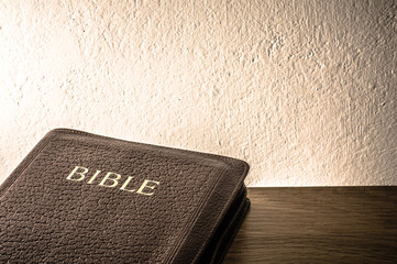 Bible on wooden table with wall background. Large copy space