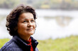© Volodymyr - An elderly woman in nature with a slight smile feels happy. Portrait of an elderly woman looking up near the river on a blurred background