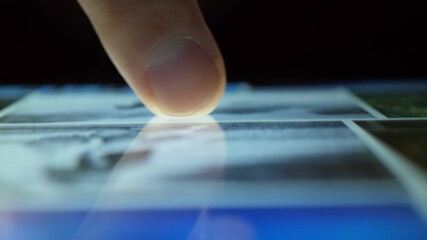 Close up Macro Man Browsing Tablet Computer With Finger. Person Using Smartphone, Browsing through Pictures on Social Network Wall. Close Up Finger Scrolling Social Media App Feed.