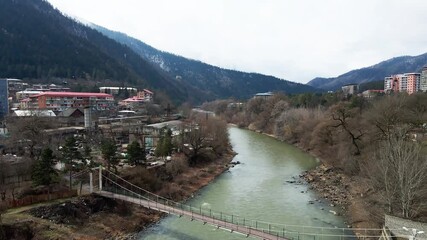 Wall Mural - Aerial drone footage. Flying over the bridge over the mountain river flowing through the city of Borjomi.