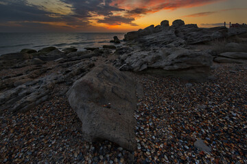 Wall Mural - Russia. Dagestan. Dawn on the seashell-strewn rocky shore of the Caspian Sea near the city embankment of Makhachkala.