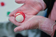 Hands in gloves hold an egg with a red thread, before painting for Easter