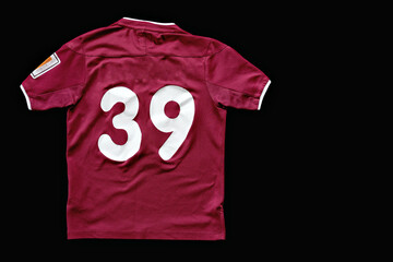 T-shirt in dark magenta color with number 39 isolated on black background top view close-up with shadow.