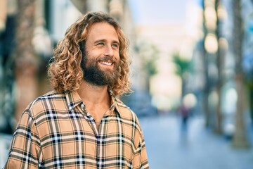 Wall Mural - Young caucasian man with long hair smiling happy at the city.