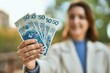 © Krakenimages.com - Young hispanic woman smiling happy holding polish zloty banknotes at the park