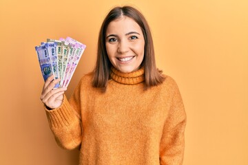 Poster - Young beautiful woman holding indian rupee banknotes looking positive and happy standing and smiling with a confident smile showing teeth