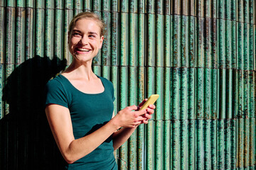 young woman with green t-sirt using yellow smartphone with copy space