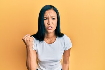 Sticker - Beautiful hispanic woman wearing casual white tshirt angry and mad raising fist frustrated and furious while shouting with anger. rage and aggressive concept.