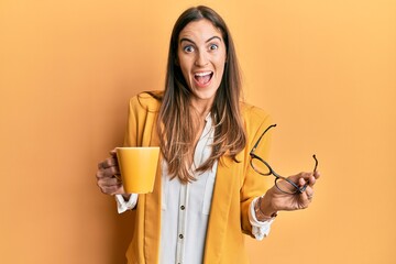 Young beautiful woman wearing business style drinking cup of coffee celebrating crazy and amazed for success with open eyes screaming excited.