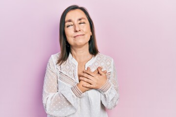 Canvas Print - Middle age hispanic woman wearing casual clothes smiling with hands on chest with closed eyes and grateful gesture on face. health concept.