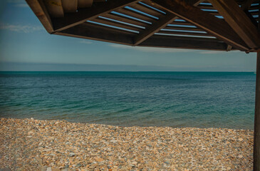 Wall Mural - Wooden beach umbrellas close up by the sea in clear weather