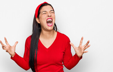 Wall Mural - Young hispanic woman wearing casual clothes crazy and mad shouting and yelling with aggressive expression and arms raised. frustration concept.