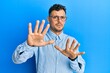 © Krakenimages.com - Young hispanic man wearing casual clothes and glasses afraid and terrified with fear expression stop gesture with hands, shouting in shock. panic concept.
