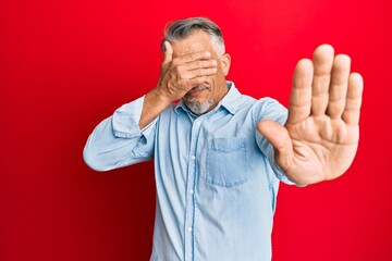 Sticker - Middle age grey-haired man wearing casual clothes covering eyes with hands and doing stop gesture with sad and fear expression. embarrassed and negative concept.