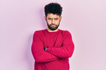 Sticker - Young arab man with beard wearing casual pink sweater skeptic and nervous, disapproving expression on face with crossed arms. negative person.