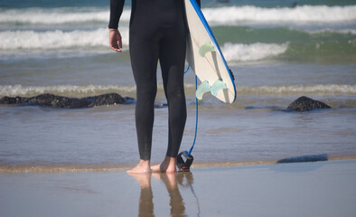 Surf - surfista com a prancha debaixo do braço a preparar-se para entrar na água do mar