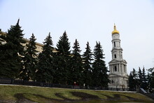 KHARKIV, UKRAINE - MARCH 29, 2019: Assumption Or Dormition Cathedral Of Kharkiv, Ukraine, Winter Day With Blue Cloudy Sky And Black Tree Silhouette Without Leaves, View From  Ground On Golden Domes