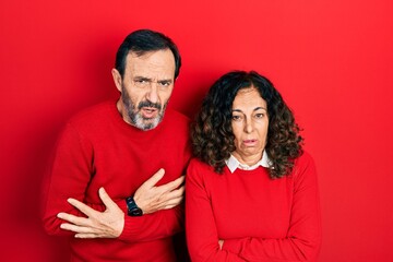 Middle age couple of hispanic woman and man hugging and standing together shaking and freezing for winter cold with sad and shock expression on face