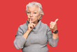 © Krakenimages.com - Senior grey-haired woman wearing casual winter sweater asking to be quiet with finger on lips pointing with hand to the side. silence and secret concept.
