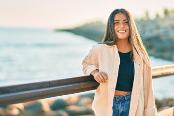 Wall Mural - Young hispanic girl smiling happy leaning on the balustrade.