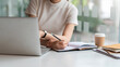 © amnaj - Close up of woman holding a pencil and taking notes at the office.