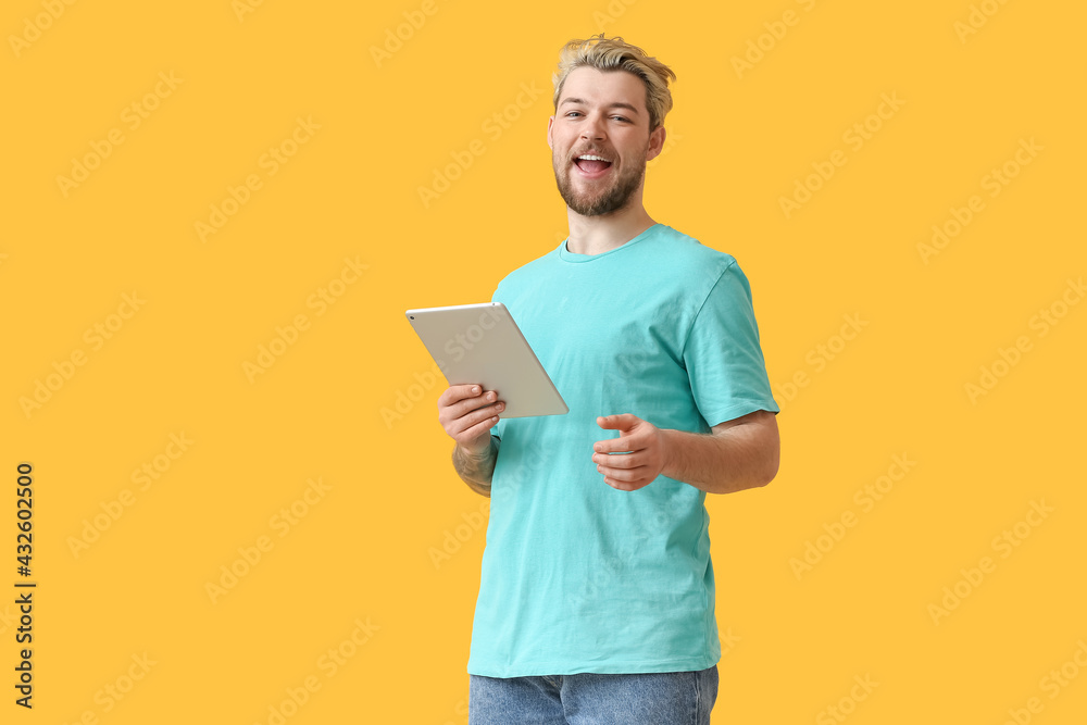 Young man with tablet computer on color background
