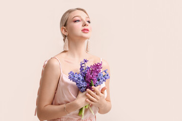 Wall Mural - Beautiful young woman with hyacinth flowers on light background