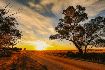 Vibrant country scene at sunset featuring dirt road in rural Australian landscape with Pyramid Hill visible in the distance