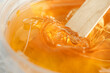 Sugar paste or wax honey in a transparent jar on a white background. Sugaring. Depilation and beauty concept. Waxing.