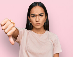 Wall Mural - Young asian woman wearing casual clothes looking unhappy and angry showing rejection and negative with thumbs down gesture. bad expression.