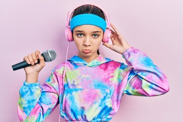 Poster - Young brunette girl singing song using microphone wearing sportswear depressed and worry for distress, crying angry and afraid. sad expression.