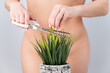 © Михаил Решетников - A naked faceless woman cuts a bush. Epilation of the bikini zone on a white background