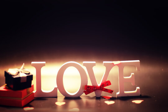 Wooden and metal letters forming word LOVE written on dark black background with lights.