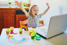 Toddler Girl Playing Modelling Clay In Front Of Laptop