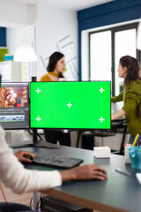Fototapete - Black videographer performing at pc with chroma key, mock up isolated display editing video footage. African editor processing film montage on green screen working in digital multimedia company