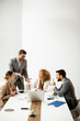 © BGStock72 - Group of young business people working and communicating while sitting at the office desk together