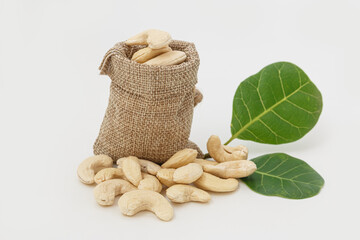 Cashew nuts with green leaf in bag isolated on white background