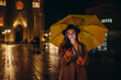 © Zamrznuti tonovi - Woman using a smartphone while holding a yellow umbrella in the night