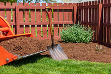 Tractor Loader With Wood Chips Or Mulch And Flowerbed. Lawncare, Gardening And Backyard Landscaping Concept