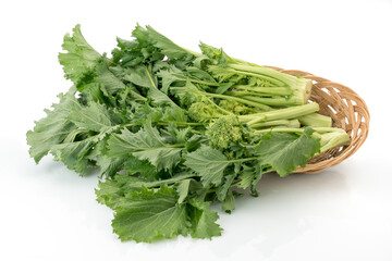 Fresh turnip tops in wicker basket, italian cime di rapa, isolated on white background