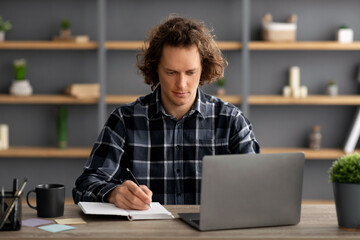 Poster - Serious Man Taking Notes Sitting At Laptop Computer In Office
