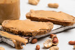 Peanut butter in a glass jar, peanuts, kitchen knife and peanut butter sandwiches on white background. Vegan food