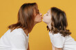 Happy woman in basic white t-shirt have fun kiss with cute child baby girl 5-6 years old. Mommy little kid daughter isolated on yellow orange color background studio. Mother's Day love family concept.