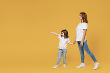 Full Length Happy Woman In Basic White T-shirt Have Fun Child Baby Girl 5-6 Years Old Hold Hands Walk Go. Mom Little Kid Daughter Isolated On Yellow Color Background Studio. Mother's Day Love Family.
