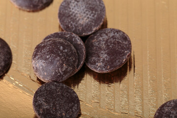 Wall Mural - Round chocolate chips on a golden surface.