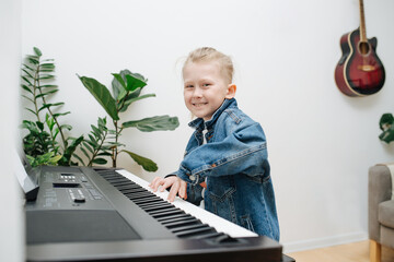 Happy boy is learning to play electric piano at home. He is enjoying himsef