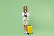 Full length traveler tourist woman in casual clothes hat hold suitcase valise scream in megaphone spread hands isolated on green background Passenger travel abroad weekends Air flight journey concept