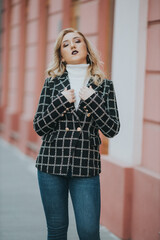 Wall Mural - Vertical shot of a blonde female posing in an elegant black and white checkered jacket