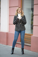 Wall Mural - Vertical shot of a blonde female posing in an elegant black and white checkered jacket